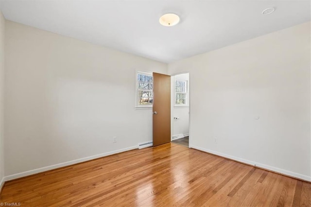 unfurnished room featuring baseboard heating and light hardwood / wood-style flooring