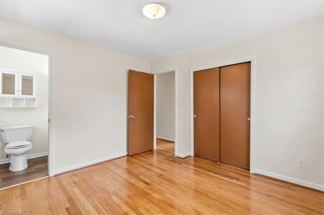 unfurnished bedroom featuring light wood-type flooring, a closet, and connected bathroom