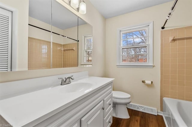 full bathroom with wood-type flooring, toilet, vanity, and tiled shower / bath combo