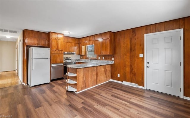 kitchen featuring kitchen peninsula, stainless steel electric stove, white fridge, and hardwood / wood-style flooring