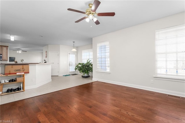 unfurnished living room with ceiling fan, a healthy amount of sunlight, and light hardwood / wood-style flooring