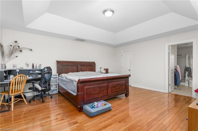 bedroom with light hardwood / wood-style flooring and a tray ceiling