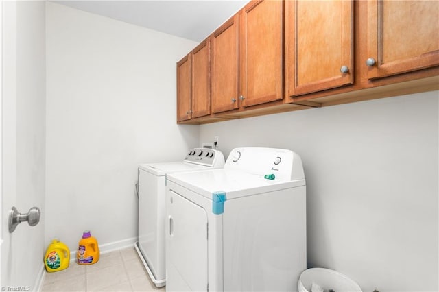 washroom featuring cabinets, light tile patterned flooring, and washing machine and clothes dryer