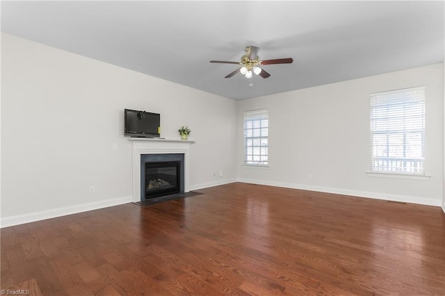 unfurnished living room featuring dark wood-type flooring and ceiling fan