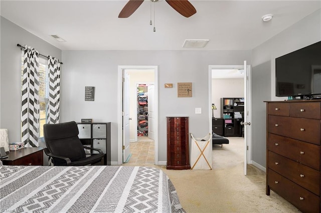 bedroom featuring a walk in closet, light colored carpet, a closet, and ceiling fan