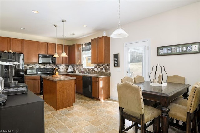 kitchen featuring sink, backsplash, a center island, black appliances, and decorative light fixtures