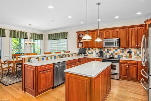 kitchen with a peninsula, a kitchen island, appliances with stainless steel finishes, light countertops, and a sink
