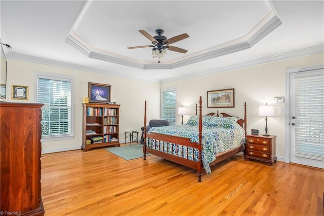 bedroom featuring a tray ceiling, light wood-style floors, and ornamental molding