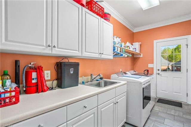 laundry room with a sink, ornamental molding, cabinet space, and washer and clothes dryer