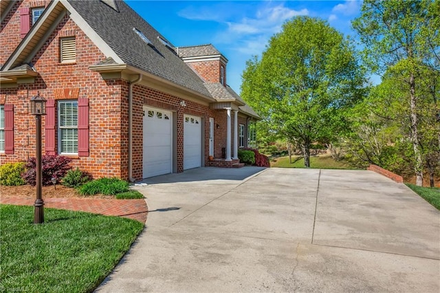 view of side of home with an attached garage, roof with shingles, concrete driveway, and brick siding