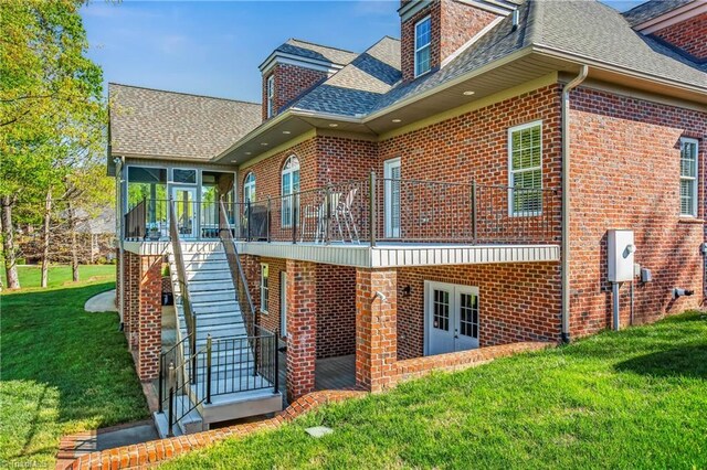 back of house with a sunroom, a lawn, stairs, french doors, and a shingled roof