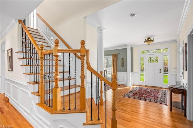 entryway featuring a decorative wall, decorative columns, ornamental molding, stairway, and wood finished floors
