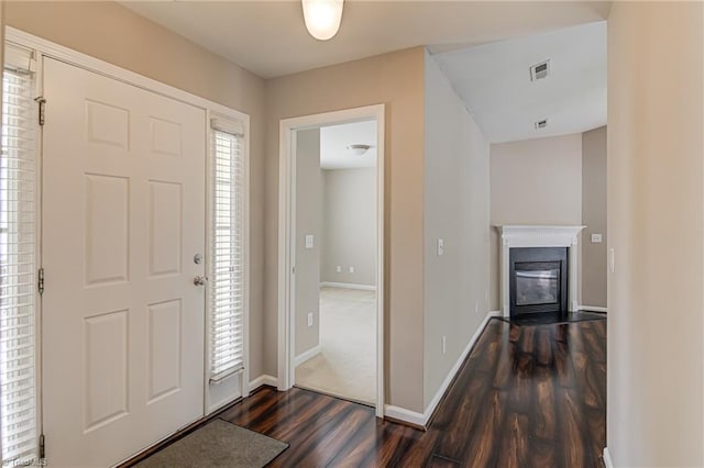 entrance foyer featuring visible vents, dark wood finished floors, a glass covered fireplace, and baseboards