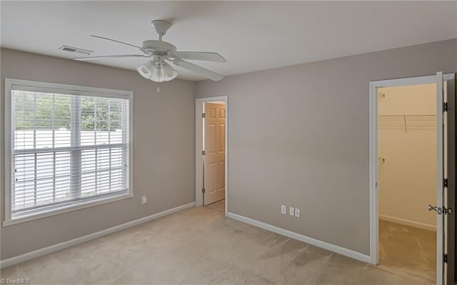 unfurnished bedroom with light carpet, baseboards, a spacious closet, visible vents, and a closet