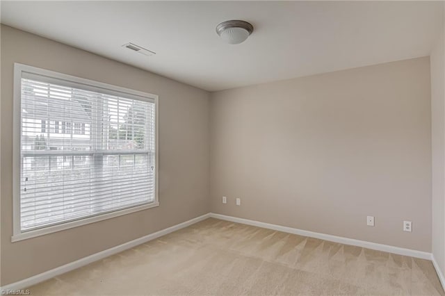 empty room with visible vents, baseboards, and light carpet