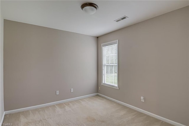 spare room with visible vents, baseboards, and light colored carpet