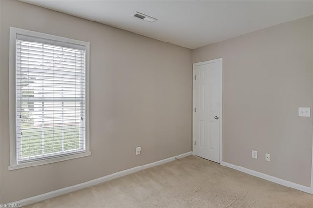 spare room featuring visible vents, baseboards, and light carpet