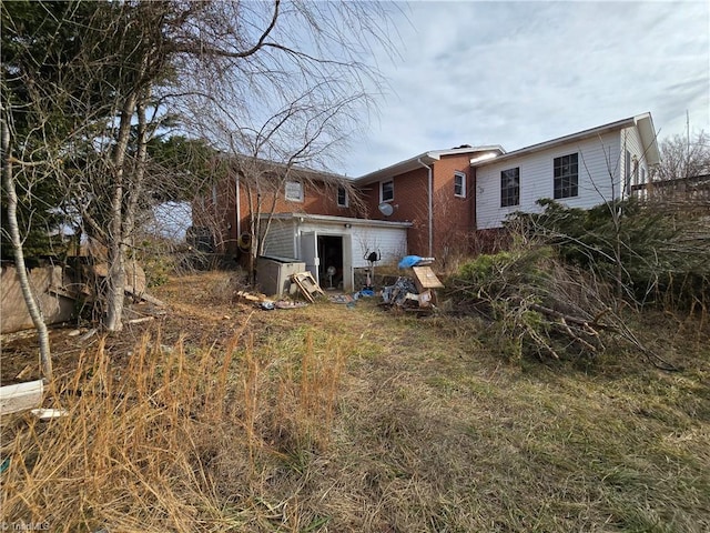 rear view of house featuring brick siding and an attached garage