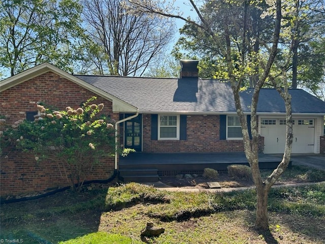 view of front facade with an attached garage, roof with shingles, a chimney, and brick siding
