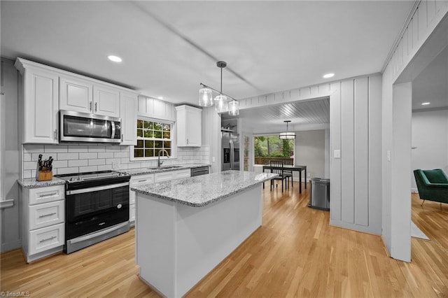 kitchen with white cabinets, decorative backsplash, light wood-type flooring, and stainless steel appliances