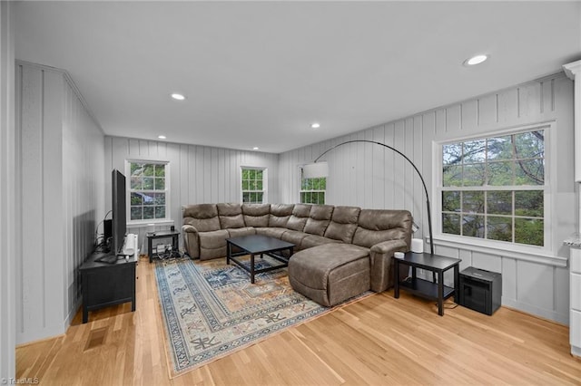 living area with recessed lighting, a decorative wall, and light wood finished floors