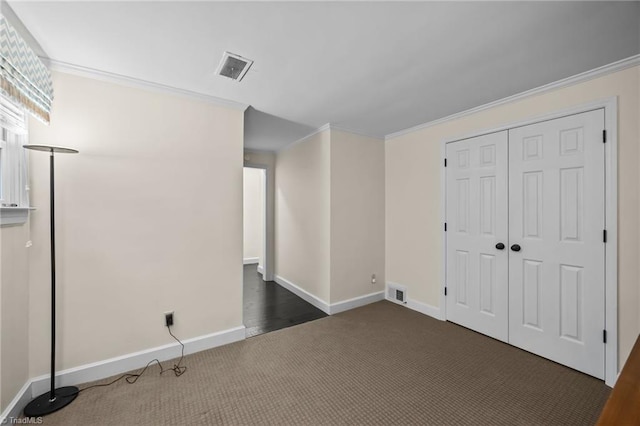 unfurnished bedroom featuring a closet, baseboards, crown molding, visible vents, and dark carpet