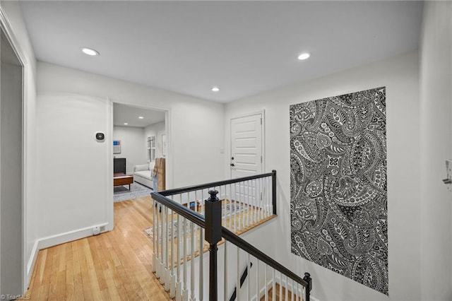 hallway featuring baseboards, an upstairs landing, recessed lighting, and light wood finished floors