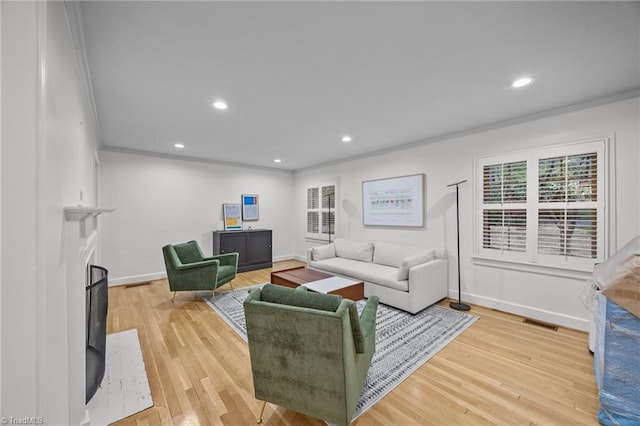living area featuring light wood finished floors, ornamental molding, visible vents, and recessed lighting