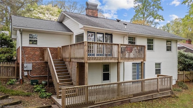 rear view of house with stairway, a wooden deck, fence, and a chimney
