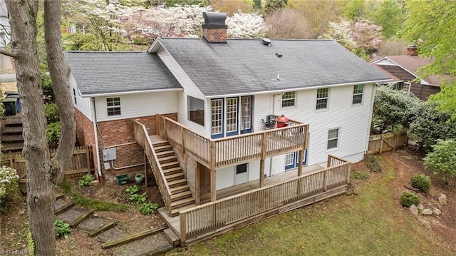 back of house featuring a deck, a chimney, fence, stairway, and brick siding