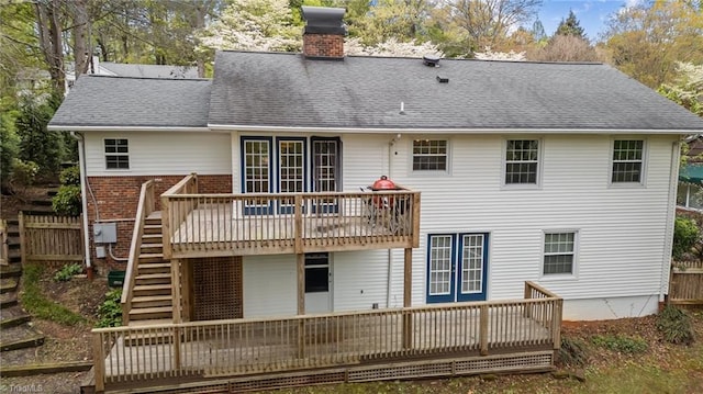 back of property with roof with shingles, a wooden deck, stairs, and a chimney