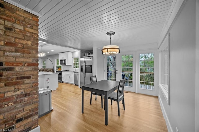 dining room with a notable chandelier, light wood-type flooring, crown molding, and wood ceiling