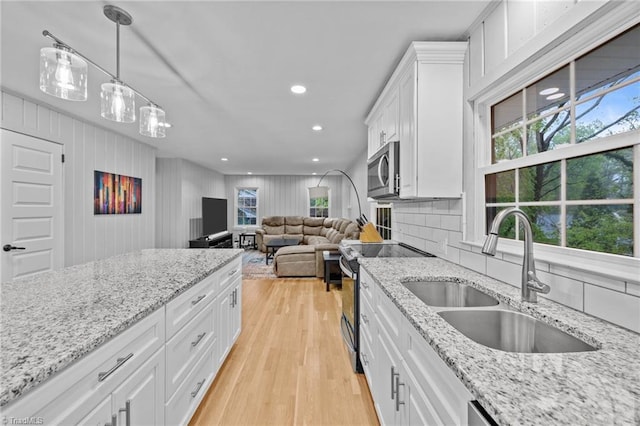 kitchen featuring tasteful backsplash, white cabinetry, light wood-style floors, appliances with stainless steel finishes, and a sink
