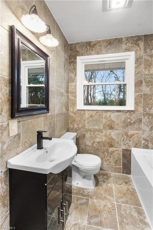 bathroom with tile walls, vanity, toilet, and a bathing tub