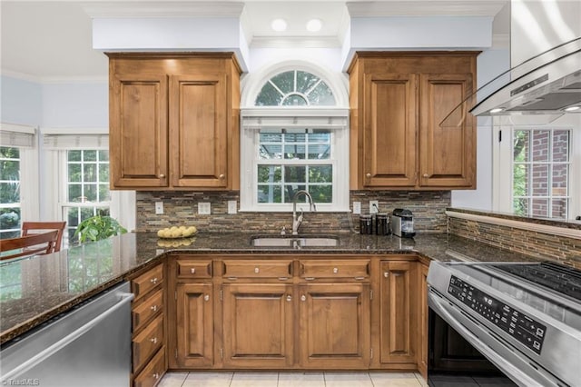 1018 Riverbend Dr, Advance, NC 27006 - kitchen with stainless steel appliances, light tile patterned flooring, dark stone counters, crown molding, and wall chimney exhaust hood