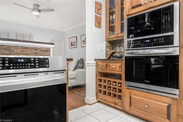 1018 Riverbend Dr, Advance, NC 27006 - kitchen featuring crown molding, light tile patterned floors, double oven, a ceiling fan, and glass insert cabinets