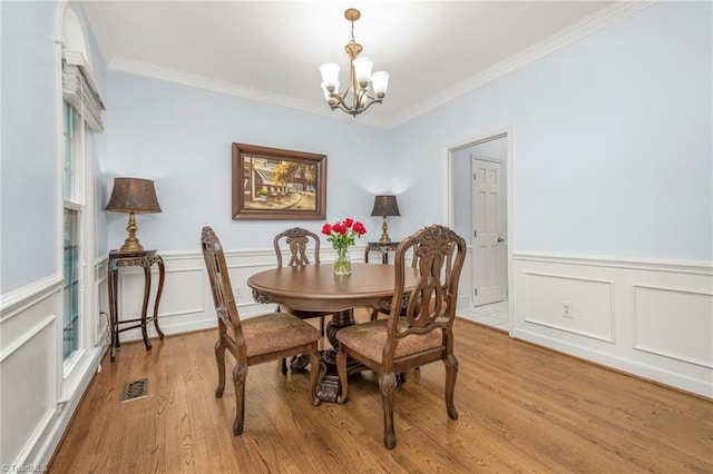 1018 Riverbend Dr, Advance, NC 27006 - dining room featuring a chandelier, crown molding, wood finished floors, wainscoting, and a decorative wall