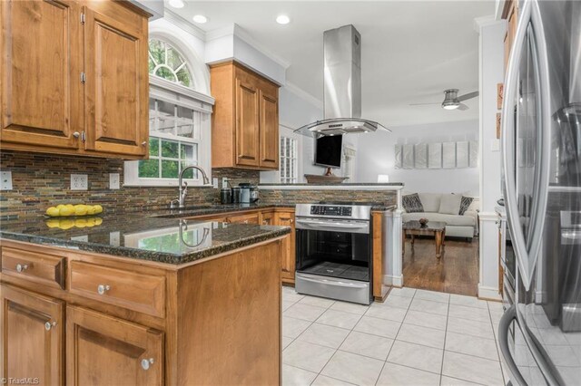 1018 Riverbend Dr, Advance, NC 27006 - kitchen featuring appliances with stainless steel finishes, a peninsula, island exhaust hood, brown cabinetry, and light tile patterned floors