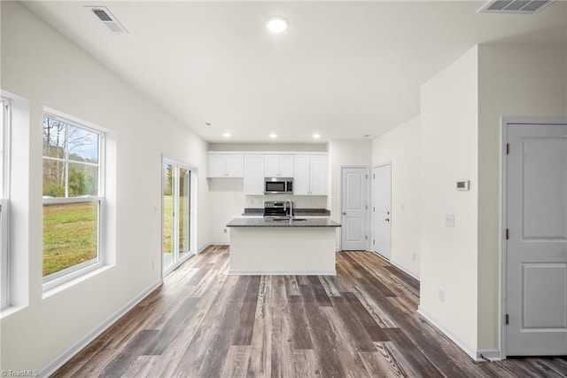 kitchen with white cabinets, sink, a kitchen island with sink, and dark wood-type flooring