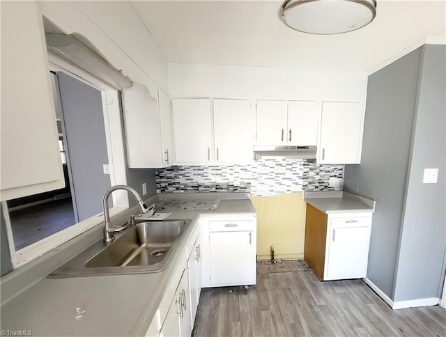 kitchen with decorative backsplash, sink, white cabinets, and light wood-type flooring