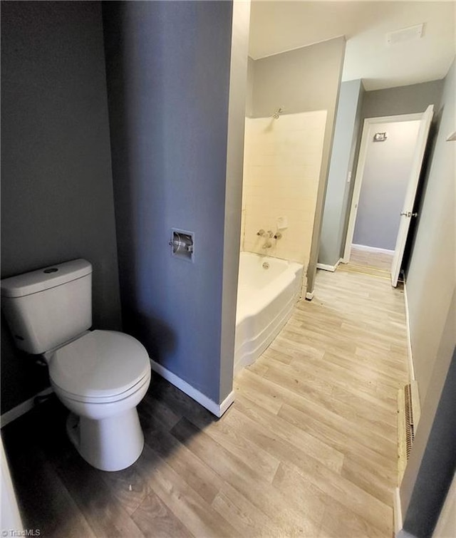 bathroom with shower / bath combination, hardwood / wood-style flooring, and toilet