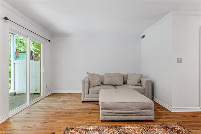living area featuring wood finished floors, baseboards, and ornamental molding