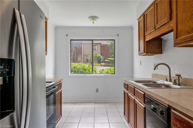 kitchen with black appliances, a sink, brown cabinetry, light tile patterned floors, and light countertops