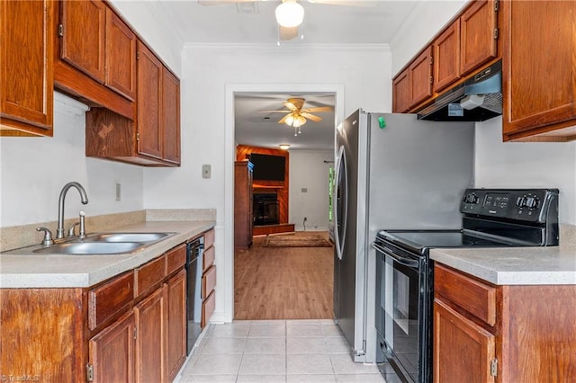 kitchen with black appliances, under cabinet range hood, a ceiling fan, a sink, and a fireplace with raised hearth