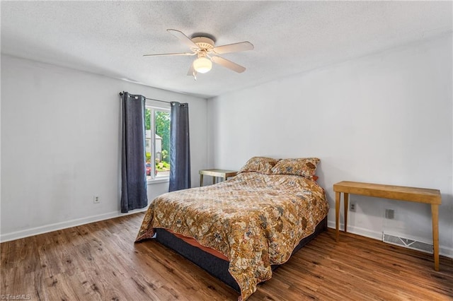 bedroom with wood finished floors, baseboards, a textured ceiling, and a ceiling fan