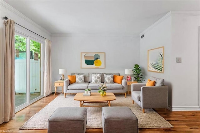 living room featuring light wood-style flooring, crown molding, and baseboards