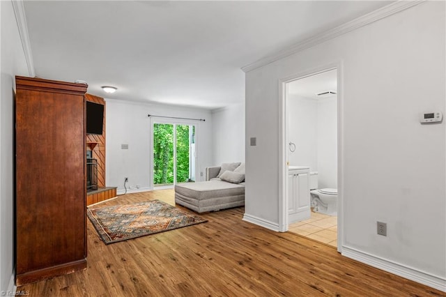 living area featuring wood finished floors, a large fireplace, baseboards, and ornamental molding
