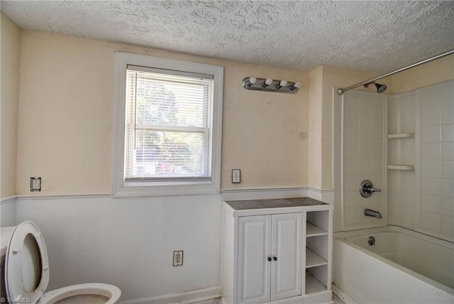 bathroom featuring toilet, a textured ceiling, and shower / tub combination