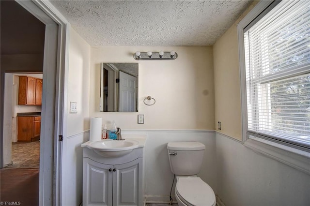 bathroom with vanity, a textured ceiling, toilet, and plenty of natural light