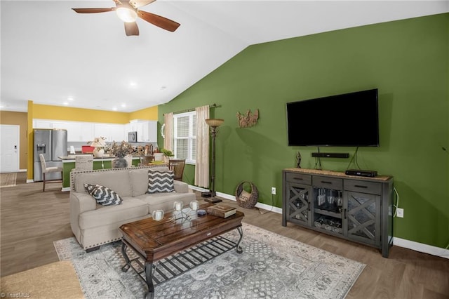 1009 Cannonade Dr, Whitsett, NC 27377 - living room featuring a ceiling fan, vaulted ceiling, baseboards, light wood-style flooring, and recessed lighting